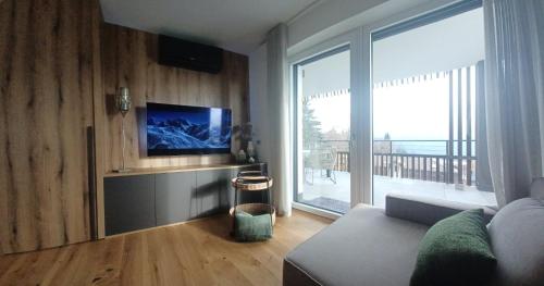 a living room with a couch and a large window at Apartment Deluxe Ossiacher See - Gerlitzen in Sattendorf