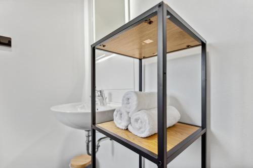 a bathroom with a sink and a shelf with towels at Mark 51-7 - Workplace - Netflix - Washer Dryer - Modern Design in Bochum