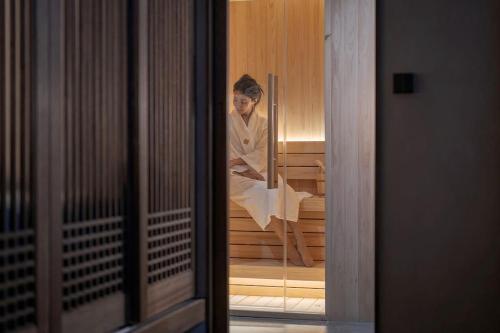 a woman sitting in a sauna looking in a mirror at Present Stay in Jeonju