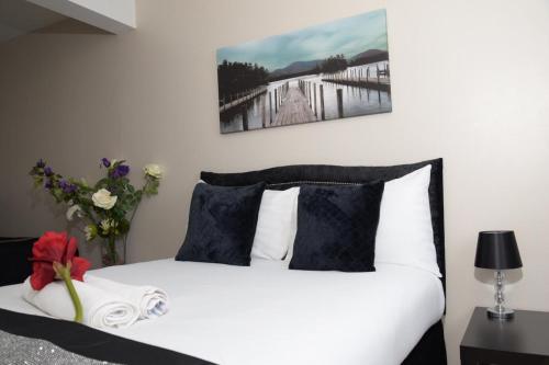 a white bed with black and white pillows and flowers at The Kyoto House - Four Spacious Cosy Bedrooms I Netflix & Large Rooms in Derby