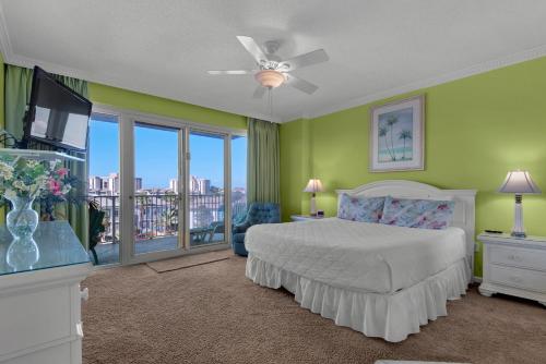 a bedroom with a bed and a television and a balcony at Leeward Key 401 in Destin