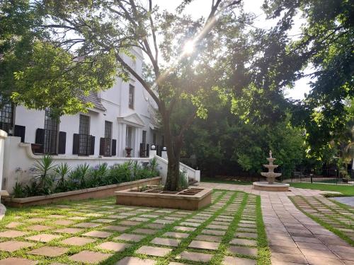 a garden in front of a white house at CONSTANTIA GUEST LODGE in Pretoria