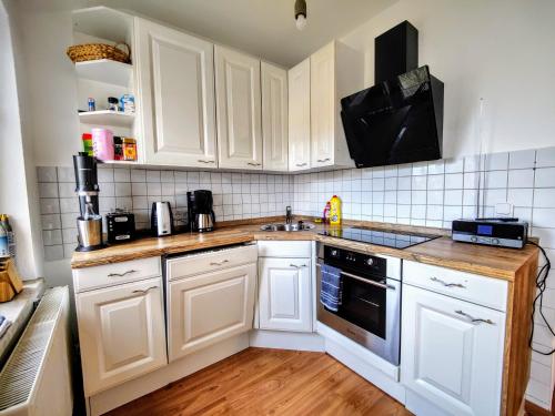 a kitchen with white cabinets and a sink at YourFavoriteBed 100m2 Designwohnung mit Vollausstattung in Plauen