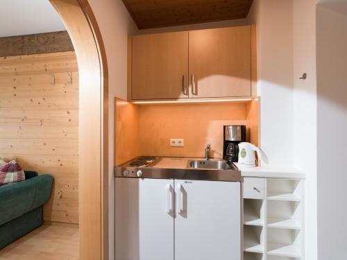 eine Küche mit weißen Schränken und einem Waschbecken in der Unterkunft Gästehaus Anker in Walchsee