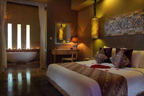 a bedroom with a bed and a tub and a bathroom at MATHIS Retreat Ubud in Ubud