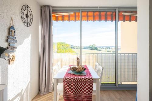 une salle à manger avec une table et une grande fenêtre dans l'établissement Charmant à 600 m des plages proche des commerces LESCLESDENICOLE, à Carqueiranne