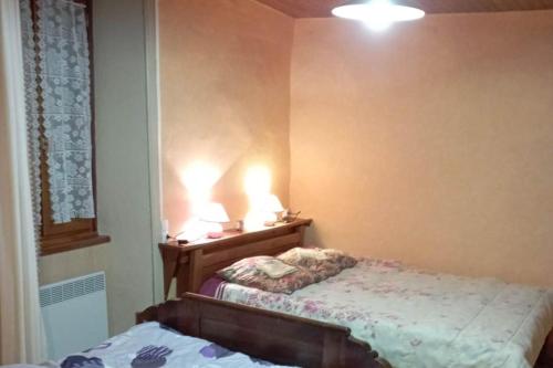 - une chambre avec un lit et deux lumières sur le mur dans l'établissement Maison atypique du Cantal proche Lot et Corrèze, à Siran