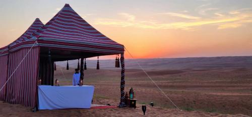 a tent in the desert with the sunset in the background at Desert Moments Glamping - full privacy in Muntarib