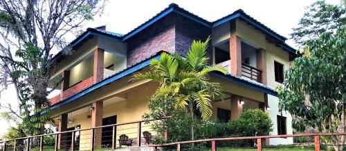 un bâtiment avec un palmier en face dans l'établissement Green Village By Hospedify, Hermosa Villa En Las Alturas con Piscina, Billar, y BBQ, à Jarabacoa