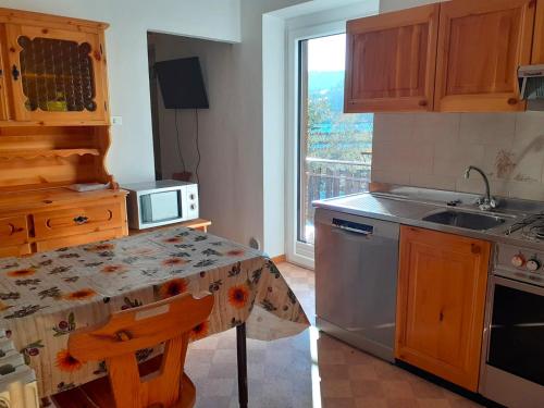 a kitchen with a table and a sink and a window at Vacanzemoena - Casa al Parco, tipologia 2 in Moena