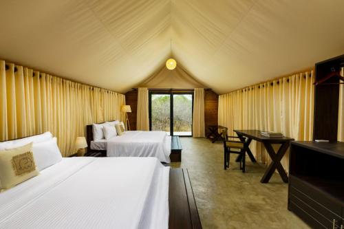 a bedroom with two beds and a desk in a tent at Makini Bush Camp, Yala in Yala