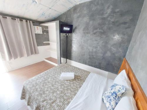 Suites por do Sol في بوزيوس: غرفة نوم صغيرة مع سرير وعلامة على الحائط
