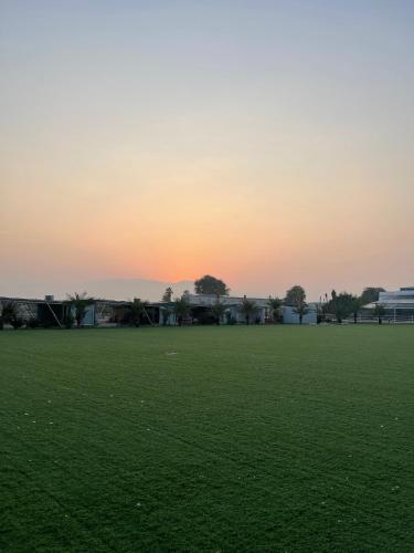 a green field with the sunset in the background at Nirvana Retreat By Patanjali Wellness Initiative in Ras al Khaimah