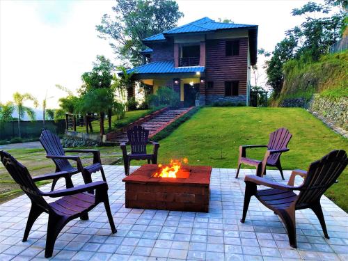 - un groupe de chaises autour d'un foyer extérieur dans une cour dans l'établissement Green Village By Hospedify, Hermosa Villa En Las Alturas con Piscina, Billar, y BBQ, à Jarabacoa