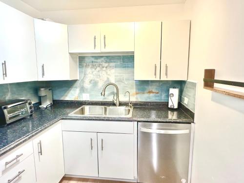 a kitchen with white cabinets and a stainless steel sink at Seashell 2 in Boynton Beach
