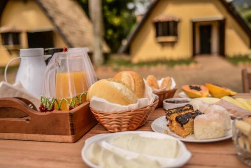 uma mesa coberta com pão e bolos em pratos em Villa das Palmeiras Chalés & Camping em São Bento do Sapucaí