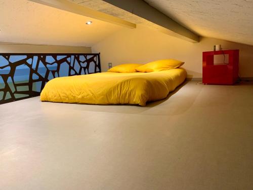 uma cama com lençóis e almofadas amarelas num quarto em Studio à la campagne em Montcornet