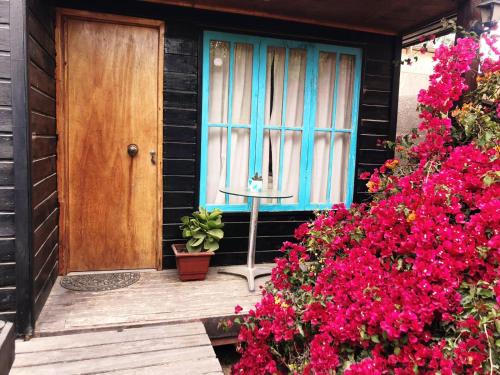 uma casa com uma porta azul e algumas flores cor-de-rosa em On Planet em Coquimbo