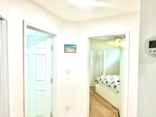 a white bedroom with a bed and a mirror at Seashell 2 in Boynton Beach