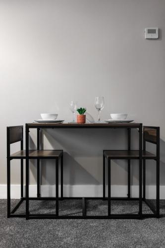 a dining table with two glasses and two chairs at City Centre Studio 1 with Kitchenette, Free Wifi and Smart TV with Netflix by Yoko Property in Middlesbrough