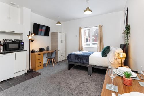 ein Schlafzimmer mit einem Bett und einem Schreibtisch sowie eine Küche in der Unterkunft City Centre Studio 1 with Kitchenette, Free Wifi and Smart TV with Netflix by Yoko Property in Middlesbrough