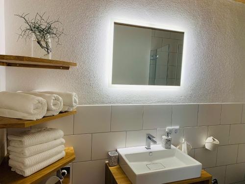 uma casa de banho com lavatório, espelho e toalhas em Dorf(er)leben Ferienwohnung im Kleinwalsertal em Mittelberg