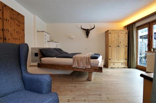 ein Schlafzimmer mit einem Bett und einem blauen Sofa in der Unterkunft Apart Lisa in Huben