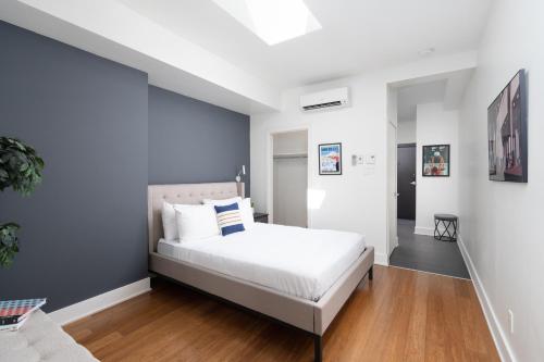 Un dormitorio con una cama blanca y una pared azul. en Hotel-Apart Prince Arthur, en Montreal