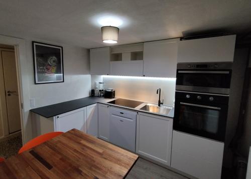 a kitchen with white cabinets and a sink and a table at Louisiana Rent in Espergærde