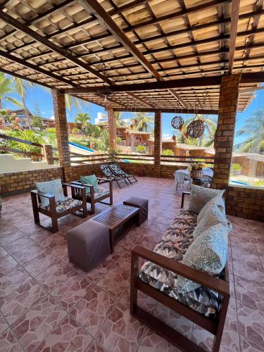 a patio with a couch and tables and a pool at Pousada Enseada do Sol in Jacumã