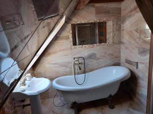 La salle de bains est pourvue d'une baignoire blanche et d'un lavabo. dans l'établissement Majerovský kaštieľ, à Vranov nad Topľou