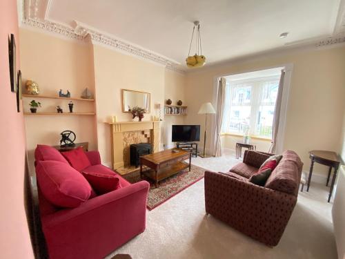 a living room with two red couches and a fireplace at St John's Flat Spacious Accomodation in Dalry