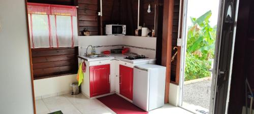 - une petite cuisine avec des placards rouges et blancs et un four micro-ondes dans l'établissement PITAYA, à Ducos