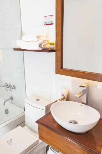 a bathroom with a sink and a toilet and a mirror at Hotel Hanan Deluxe in Arequipa