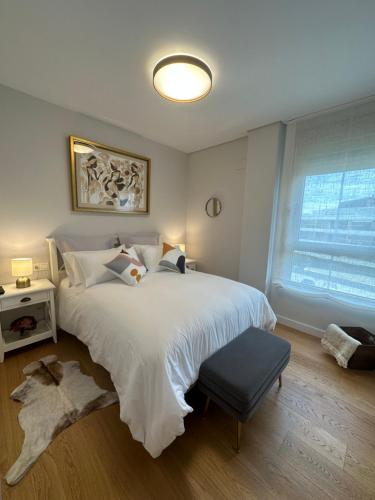Un dormitorio con una gran cama blanca y una ventana en A estrenar amplio con piscina y parking en Getxo