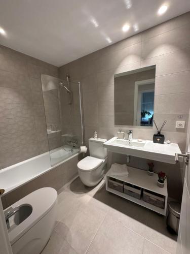 uma casa de banho com um WC, um lavatório e um chuveiro em A estrenar amplio con piscina y parking em Getxo