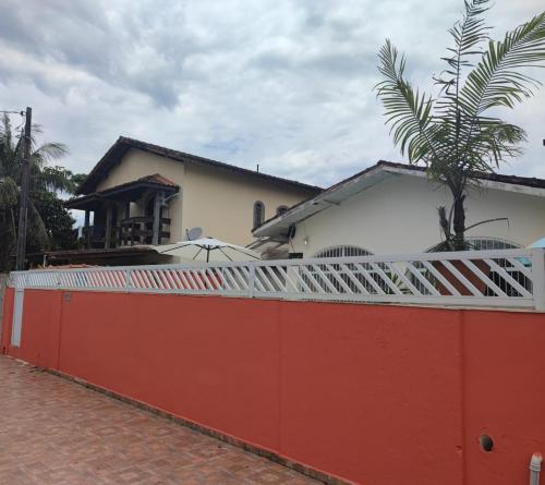 ein roter Zaun vor einem Haus in der Unterkunft Jdu Hostel e Bar in Bertioga