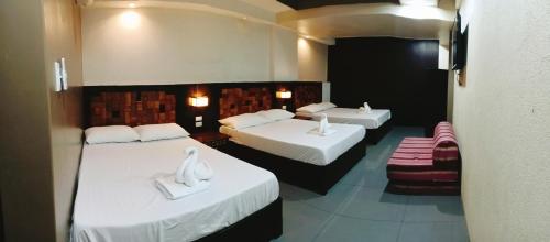 Dos camas en una habitación de hotel con cisnes. en Westgate Hotel, en Laoag