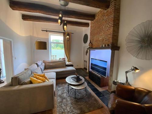 - un salon avec un canapé, une télévision et une table dans l'établissement La Dépendance du Château, à Namur
