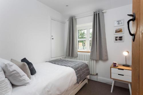 a white bedroom with a bed and a window at Forge Cottage in Winchcombe
