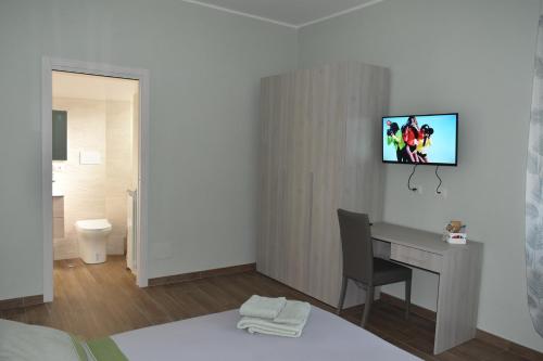 ein Hotelzimmer mit Schreibtisch und Fernseher an der Wand in der Unterkunft Armonia family B&b in Crotone