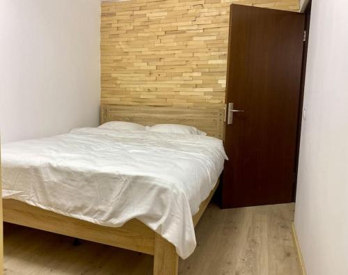 1 dormitorio con 1 cama y puerta de madera en Apartament C&C, en Voineasa