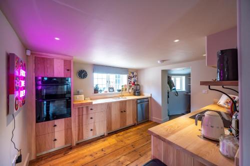 a large kitchen with wooden floors and a purple ceiling at Number 27 by Big Skies Cottages in Holt