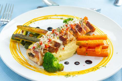 a plate of food with meat and vegetables on a table at Skylight Suites Hotel in San Felipe de Puerto Plata