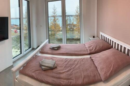 two beds in a room with large windows at Casa Ida am Hainer See in Neukieritzsch