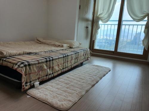 a bed and a rug in a room with a window at Cozy House in Daegu