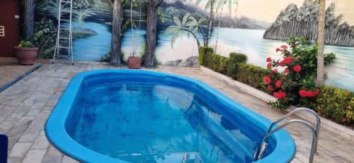 a swimming pool in front of a wall with a painting at Excelente Casa no Bairro Mundo Novo com piscina in Manaus