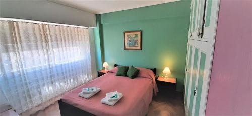 1 dormitorio con 1 cama rosa y 2 toallas en Departamento 2 ambientes TORRE LAFAYETTE Centro Mar del Plata en Mar del Plata