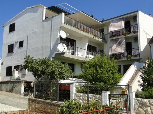 een wit appartementencomplex met balkons en bomen bij Lucija in Primošten