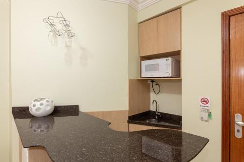 a kitchen with a black counter top and a microwave at Slim São José Zion in São José